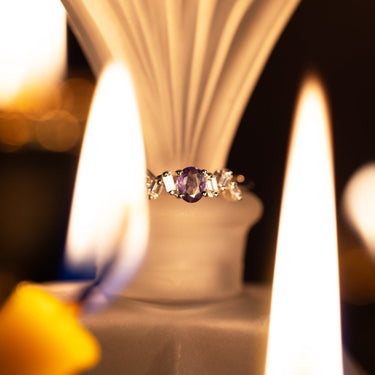 0.25ct natural alexandrite oval cut ring in 18k white gold with six baguette diamonds, showcasing strong color change from green to purple.